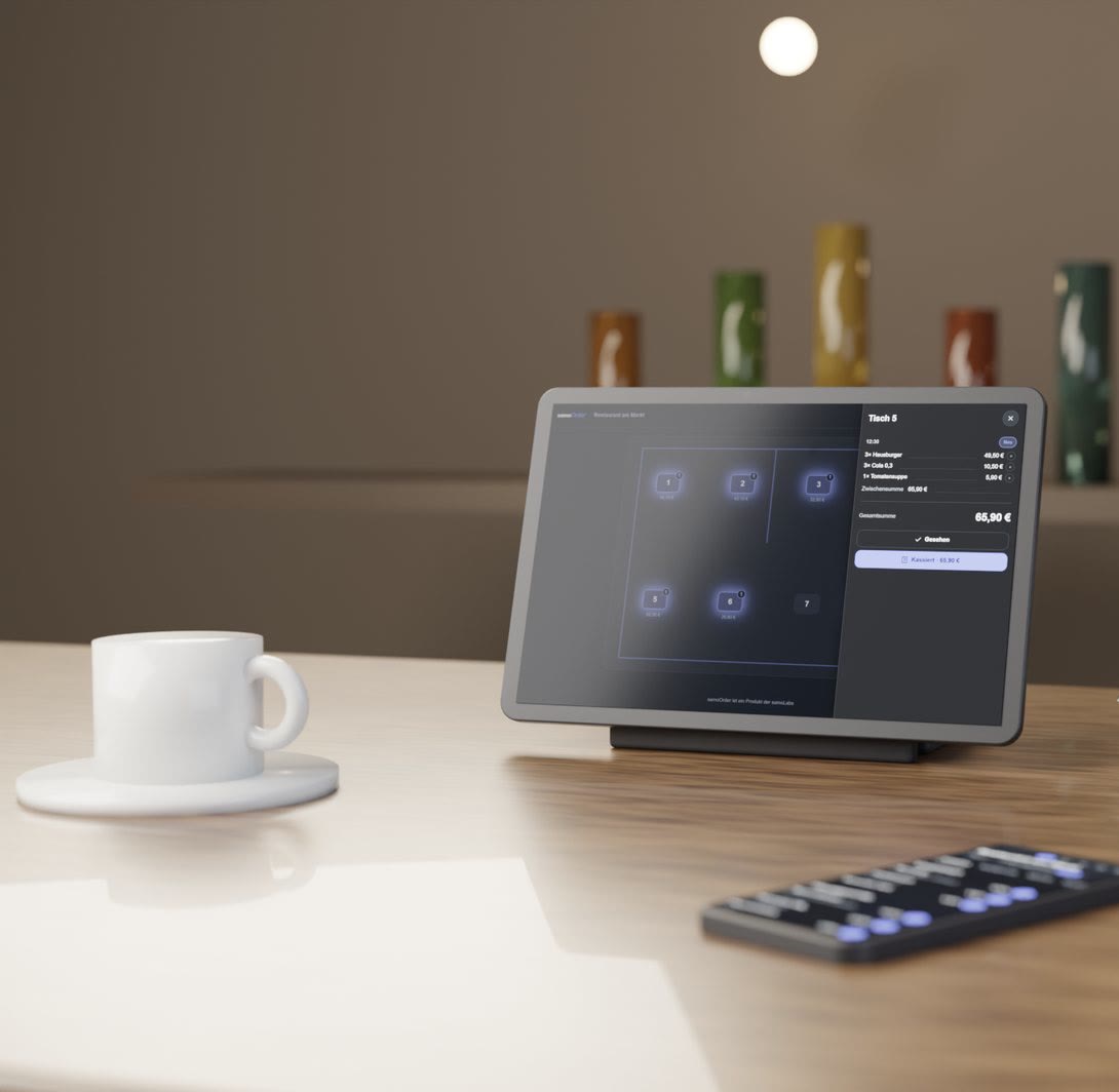 Theken-Tablet mit geöffneter Tischansicht auf einem Holztresen, daneben eine Espressotasse und ein Diensthandy